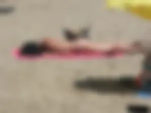 Brunette lady topless and in a black thong on the beach