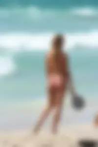 Topless girl in a tiny thong on the beach playing paddle ball
