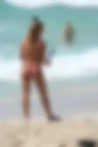 Topless girl in a tiny thong on the beach playing paddle ball