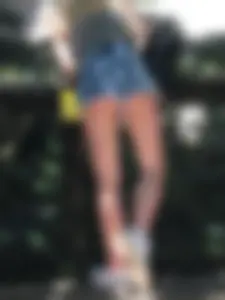 Low angle photo of a petite ass in fringed denim mini shorts and long slim legs
