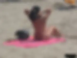 Brunette lady topless and in a black thong on the beach