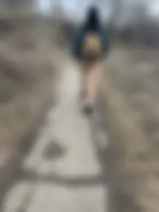 Candid girl wearing pants and a backpack walking down a suburban road