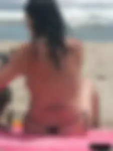 Brunette lady topless and in a black thong on the beach