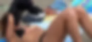 Lady in black bikini showing some pubes while laying out