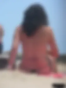 Brunette lady topless and in a black thong on the beach