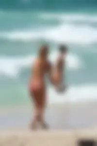 Topless girl in a tiny thong on the beach playing paddle ball