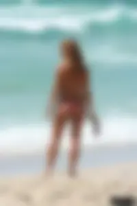 Topless girl in a tiny thong on the beach playing paddle ball