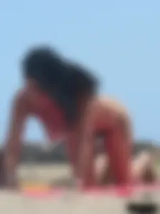 Brunette lady topless and in a black thong on the beach