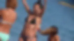 A sexy skinny girl on the beach in a bikini with sexy friends in bikinis