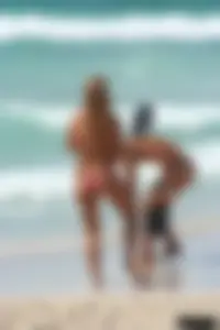 Topless girl in a tiny thong on the beach playing paddle ball
