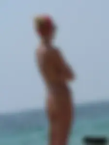 Topless skinny blonde lady in a g-string bikini at the beach