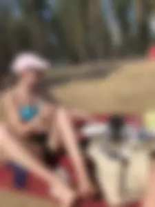 Skinny Girl in Swimsuit Sitting on the Ground in a Park