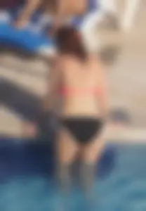 Sexy red haired girl in pink and black bikini at the pool