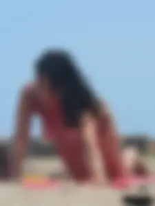 Brunette lady topless and in a black thong on the beach
