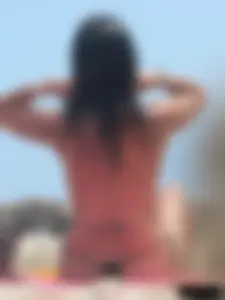 Brunette lady topless and in a black thong on the beach