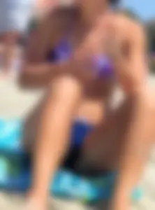 Sexy girl laying on the beach in a blue and purple bikini