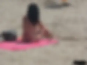 Brunette lady topless and in a black thong on the beach