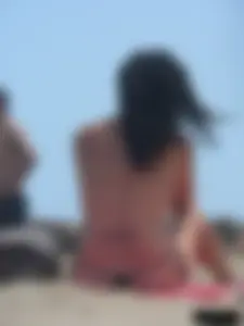 Brunette lady topless and in a black thong on the beach