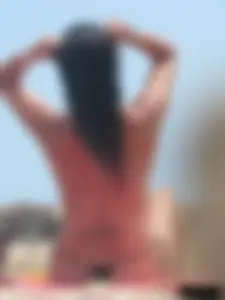 Brunette lady topless and in a black thong on the beach