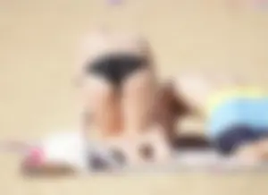 Sexy girl on the beach laying out and bending over in her bikini