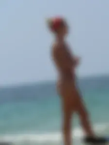 Topless skinny blonde lady in a g-string bikini at the beach