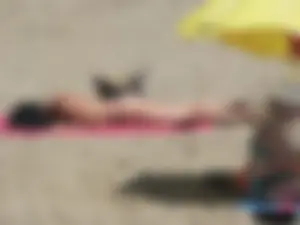 Brunette lady topless and in a black thong on the beach