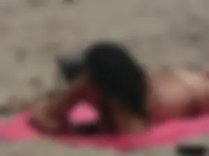Brunette lady topless and in a black thong on the beach
