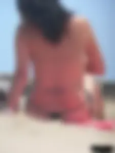 Brunette lady topless and in a black thong on the beach