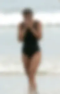 Skinny sexy lady on the beach in a black swimsuit