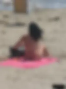 Brunette lady topless and in a black thong on the beach