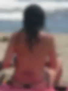 Brunette lady topless and in a black thong on the beach