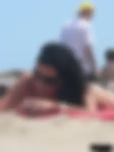 Brunette lady topless and in a black thong on the beach
