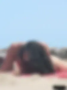 Brunette lady topless and in a black thong on the beach
