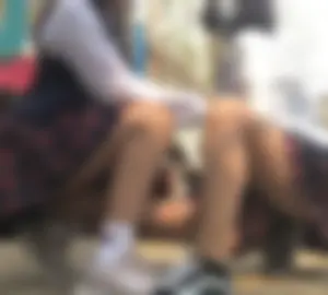 Group of Young Girls in Uniform Skirts Showing Off Their Legs on a Suburban Playground - One Touching Another's Legs