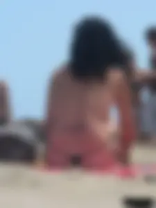 Brunette lady topless and in a black thong on the beach