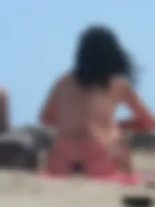 Brunette lady topless and in a black thong on the beach
