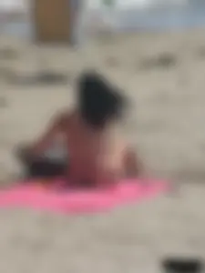 Brunette lady topless and in a black thong on the beach