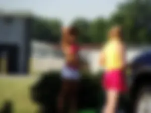 Group of cute girls at a car wash in bikinis and shorts