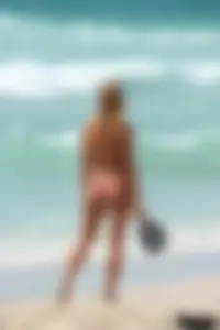 Topless girl in a tiny thong on the beach playing paddle ball