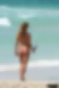Topless girl in a tiny thong on the beach playing paddle ball