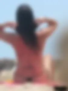 Brunette lady topless and in a black thong on the beach