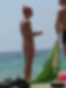 Topless skinny blonde lady in a g-string bikini at the beach
