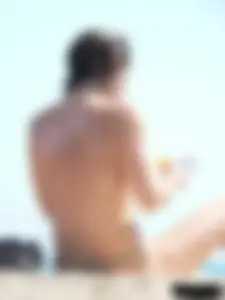 Topless beach milf looking sexy in a tiny g-string bikini