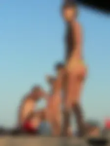 Topless girl on the beach with small boobs wearing a green thong bikini
