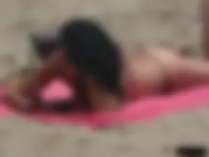 Brunette lady topless and in a black thong on the beach