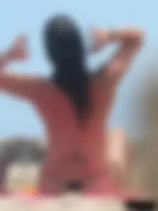 Brunette lady topless and in a black thong on the beach