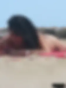 Brunette lady topless and in a black thong on the beach