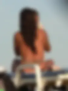 Topless tattooed lady on the beach with fake big tits