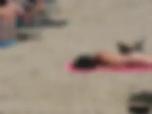 Brunette lady topless and in a black thong on the beach