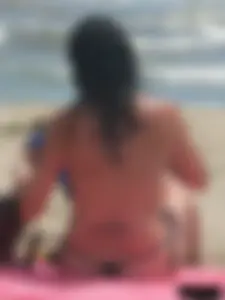 Brunette lady topless and in a black thong on the beach
